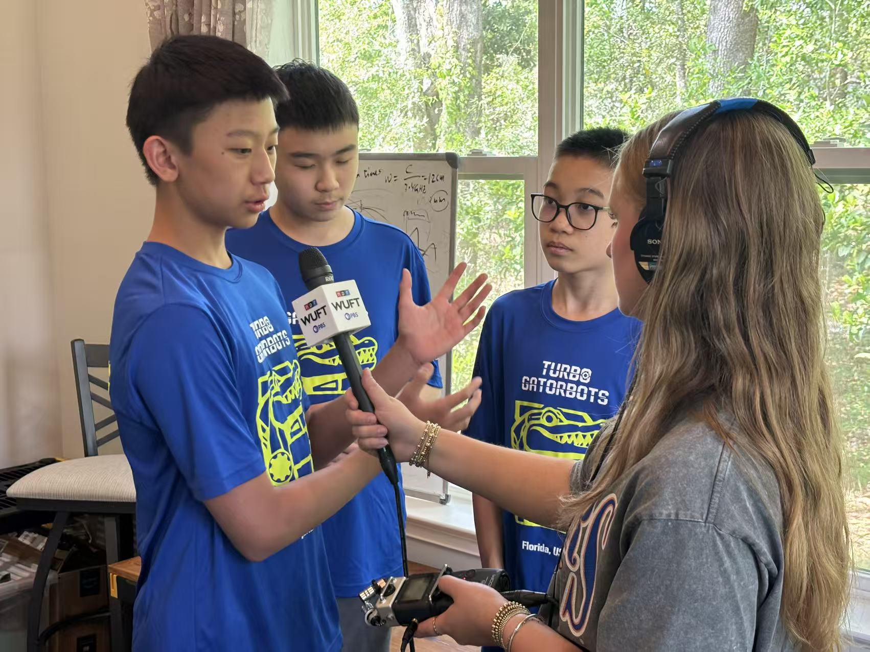 A Turbo Gatorbots team member talking with a reporter while teammates listen